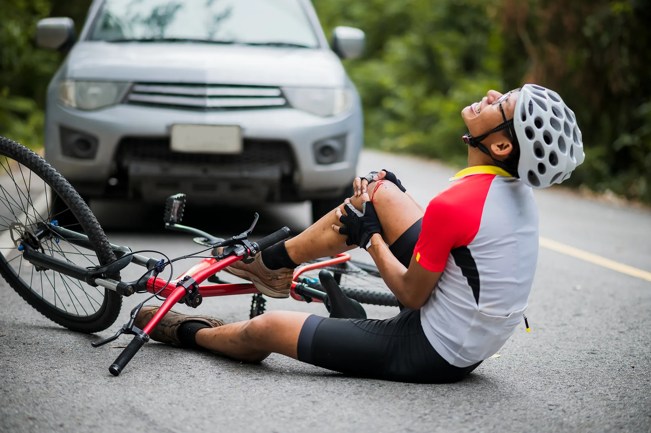 injured bicyclist next to car